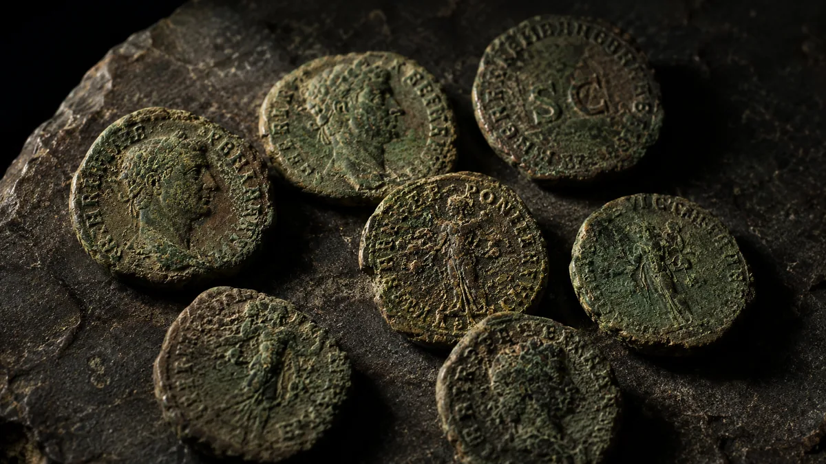 Ancient bronze coins with green patina on dark stone
