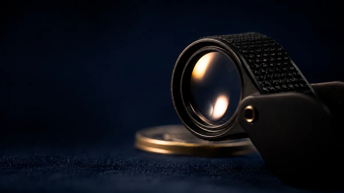 Jeweler's loupe on a dark surface with a coin behind it