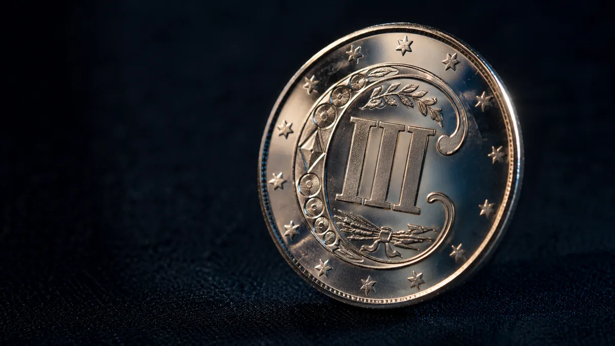 Small silver coin with a Roman numeral design